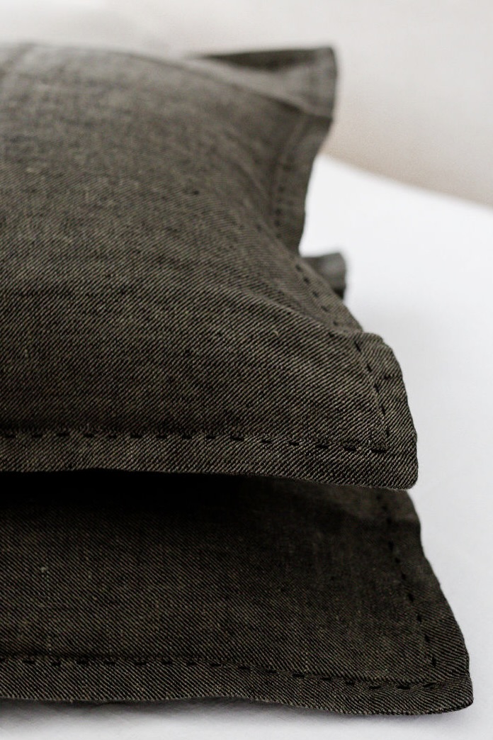 Close-up of dark fabric with visible stitching along a folded edge, showing textile texture and seams.